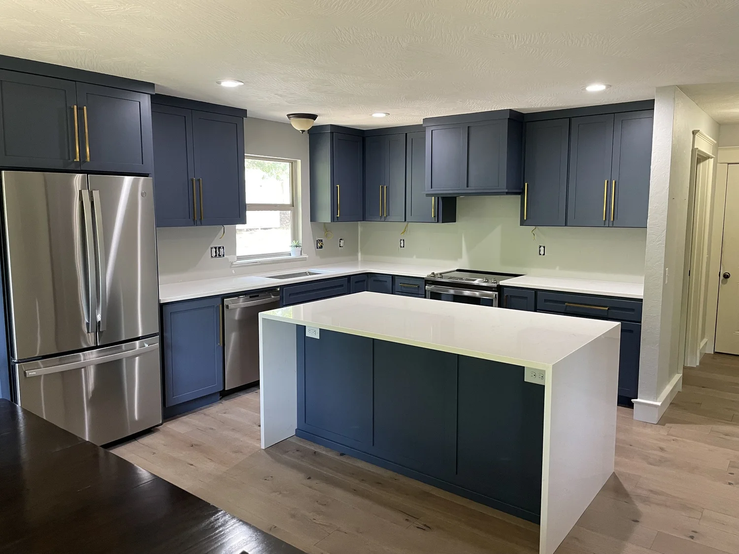 Custom deep blue shaker kitchen with brass hardware and waterfall island