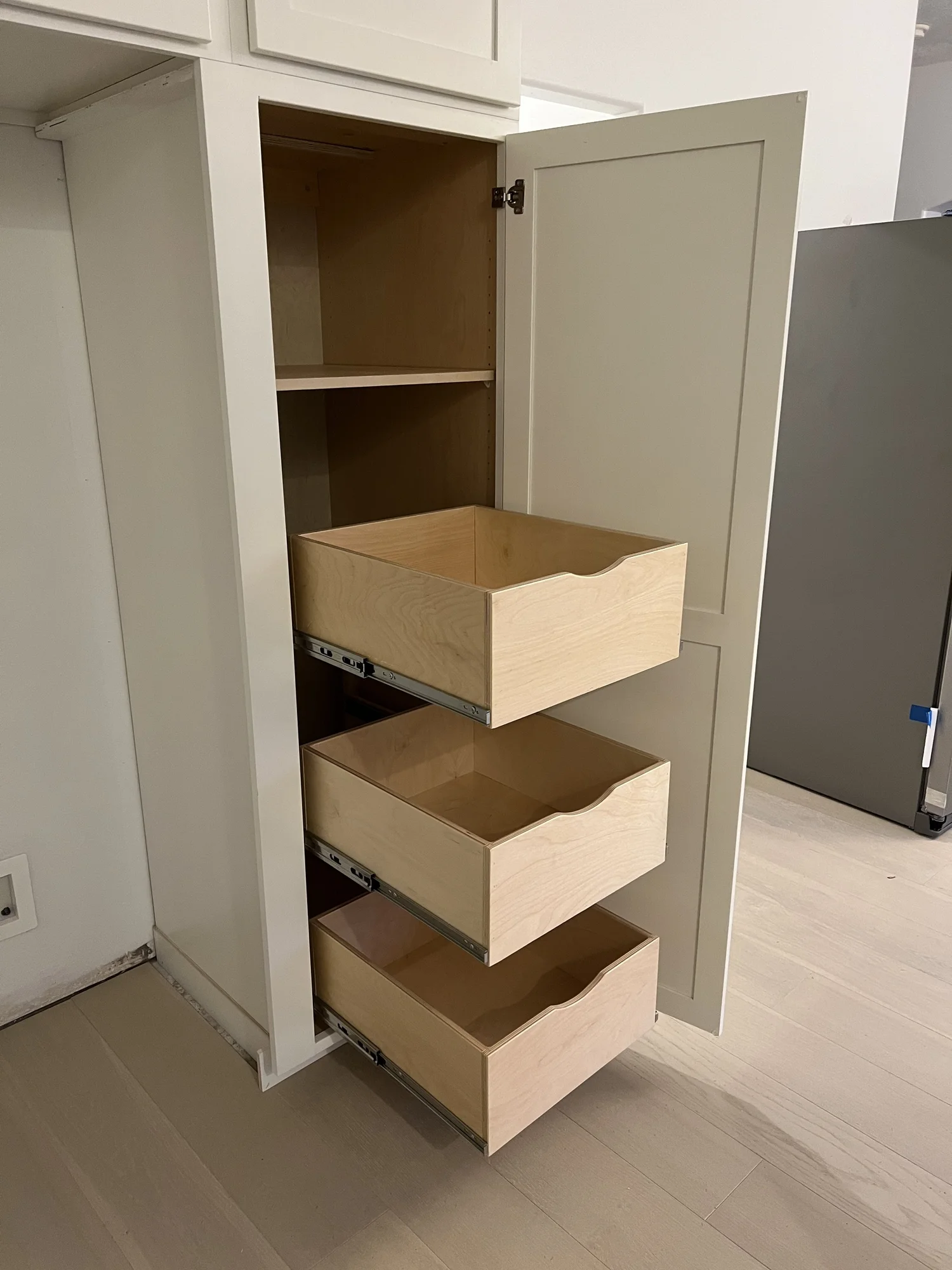 Tall custom cabinet with three open pull-out drawers
